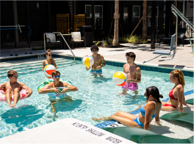 A group of young people at the pool with floats and balls